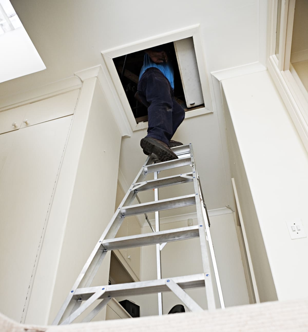 A man heads up a steep ladder into loft or attic space
