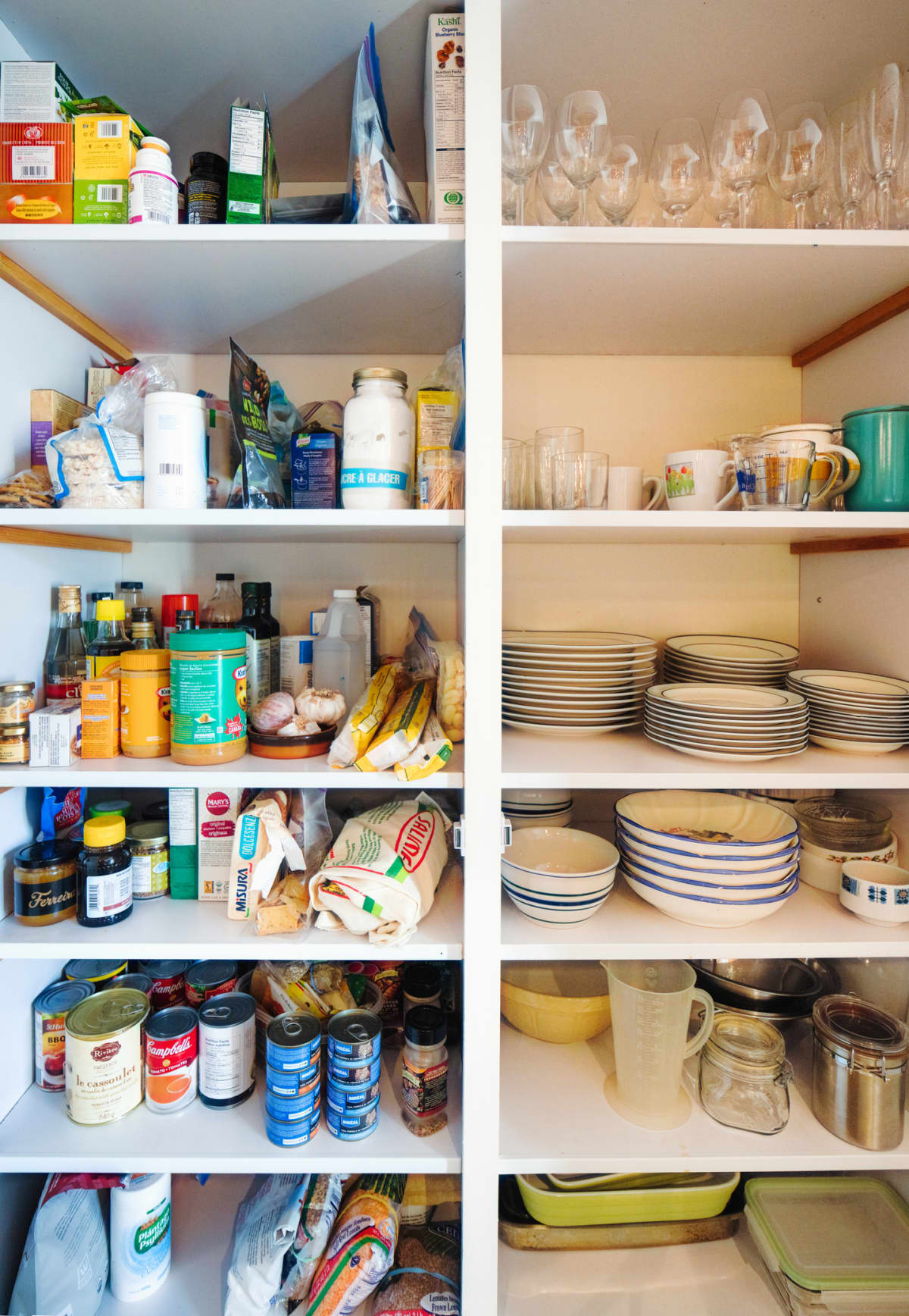 This photograph of a lived-in Apartment's Kitchen Pantry includes a section to the left for various food staples and to the right for dishes and crockery.