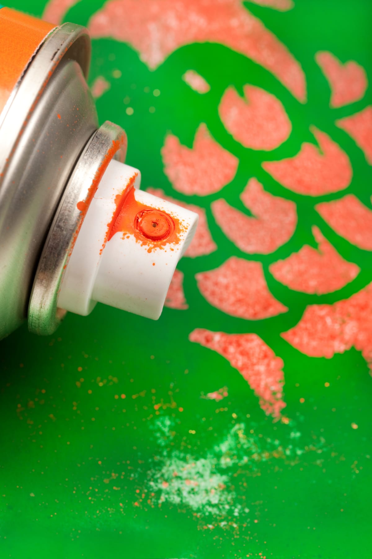 A spray paint can on a green and orange background
