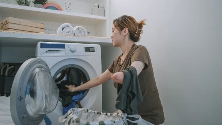 A woman placing laundry in a dryer