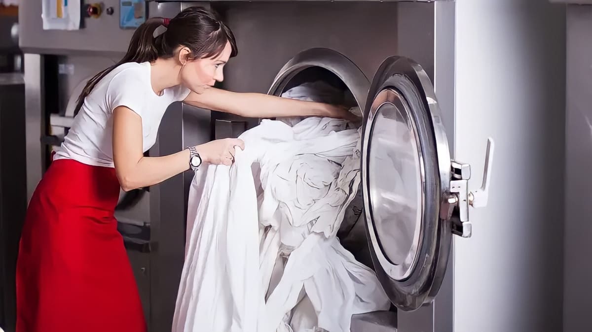 A woman pulling sheets from a dryer