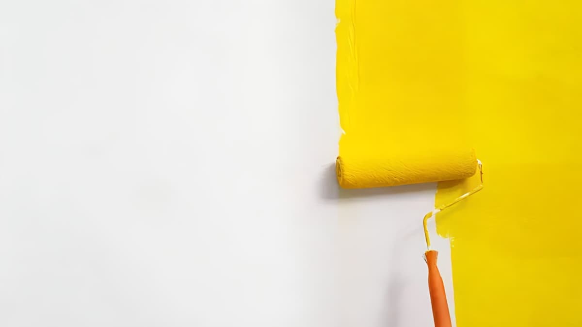 Paint roller painting a wall yellow